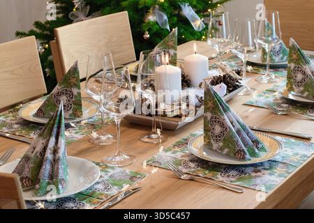 Gemütliches Heim-Weihnachtsinnenraum, festliches Tischarrangement und Weihnachtsbaum im Hintergrund. Stockfoto