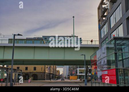 Ein Fußgänger genießt einen Spaziergang auf einem erhöhten Gehweg, während sich die Fahrzeuge in einem belebten Stadtgebiet bewegen. Stockfoto
