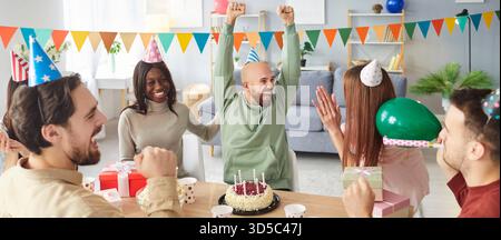 Glücklicher Mann, der die Hände hebt, Geburtstag feiert, mit Freunden jubelt und gemeinsam Party genießt. Stockfoto