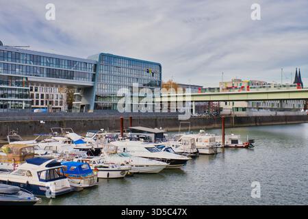 Die Boote legen in einem belebten Stadthafen mit moderner Architektur und einer Brücke im Hintergrund an. Stockfoto