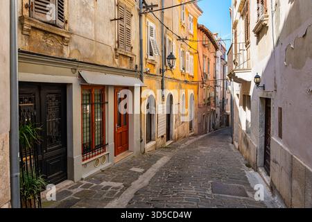 Malerische Straße mit Kopfsteinpflasterboden und farbenfrohen alten Häusern in der Küstenstadt Piran, Slowenien. Stockfoto