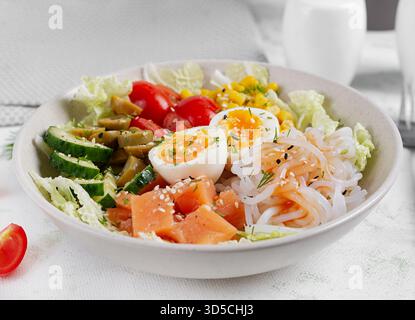 Buddha Schüsseln mit Lachs, gekochtem Ei, Tomaten, Mais, Gurke, Shirataki-Nudeln und Sesam. Asiatische Küche. Stockfoto