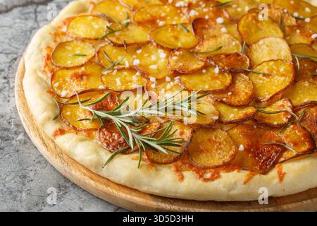 Frisch gebackene Pizza mit Kartoffelgemüse und Rosmarin Nahaufnahme auf dem Holzbrett auf dem Tisch. Horizontal Stockfoto