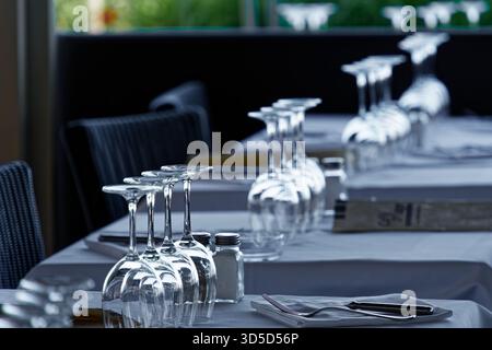 Ein Tisch mit Weißweingläsern steht bereit, damit die Restaurantgäste bei schönem Wetter im Freien ein Mittagessen genießen können. Stockfoto