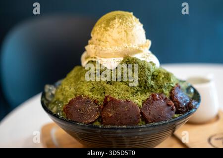 Grüner Tee Bingsu mit roten Bohnen und Eis darauf, serviert in einer Schüssel Stockfoto