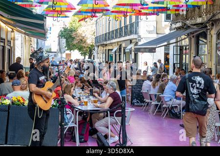 Rosa Straße Lissabon, offiziell Rua Nova do Carvalho genannt, Straße mit rosa Pflaster und mehrfarbigen Regenschirmen, die darüber hängen, Portugal, Europa Stockfoto