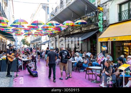 Rosa Straße Lissabon, offiziell Rua Nova do Carvalho genannt, Straße mit rosa Pflaster und mehrfarbigen Regenschirmen, die darüber hängen, Portugal, Europa Stockfoto