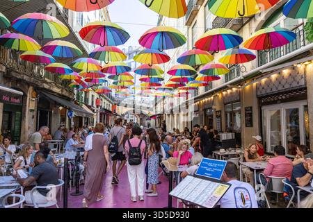 Rosa Straße Lissabon, offiziell Rua Nova do Carvalho genannt, Straße mit rosa Pflaster und mehrfarbigen Regenschirmen, die darüber hängen, Portugal, Europa Stockfoto