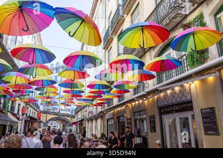 Rosa Straße Lissabon, offiziell Rua Nova do Carvalho genannt, Straße mit rosa Pflaster und mehrfarbigen Regenschirmen, die darüber hängen, Portugal, Europa Stockfoto