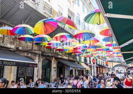 Rosa Straße Lissabon, offiziell Rua Nova do Carvalho genannt, Straße mit rosa Pflaster und mehrfarbigen Regenschirmen, die darüber hängen, Portugal, Europa Stockfoto