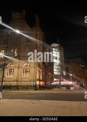 Wunderschön beleuchtetes historisches Steingebäude in Leeds, West Yorkshire, England, bei Nacht mit Ampelwegen fotografiert Stockfoto