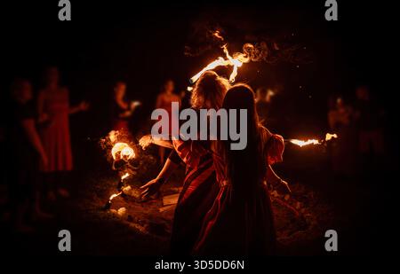 Eine bezaubernde Feuertänzerin zeigt ihr Talent während einer Vorstellung mit faszinierenden Flammen. Stockfoto