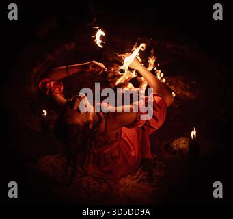 Eine bezaubernde Feuertänzerin zeigt ihr Talent während einer Vorstellung mit faszinierenden Flammen. Stockfoto