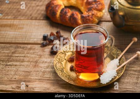 Türkischer schwarzer Tee. Eine Glasschale türkischer schwarzer Tee und knuspriger türkischer traditioneller Bagel auf altem Rustick-Hintergrund. Frühstücksgebäck-Konzept. Traditionelles türkisches Heißgetränk. Stockfoto
