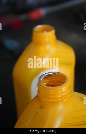 Eine Nahaufnahme von zwei offenen, hellgelben Kunststoffflaschen mit Automotoröl, die auf den Gewinden sichtbar sind, mit einem zerrissenen silbernen Sicherheitssiegel. Stockfoto