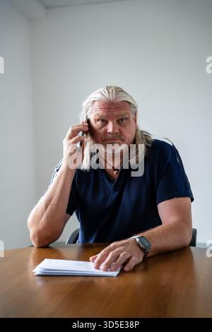 Senior Geschäftsmann mit langem Hörvermögen und Smartphone, der in die Kamera schaut Stockfoto