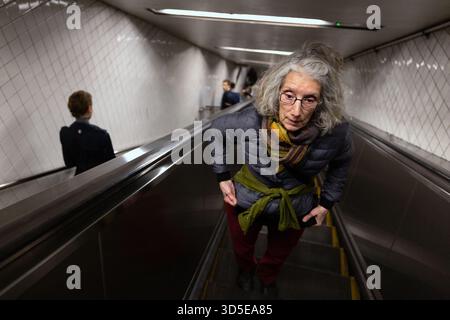 Ältere Frau, die auf dem Escalator in der U-Bahn-Station New York City reitet Stockfoto