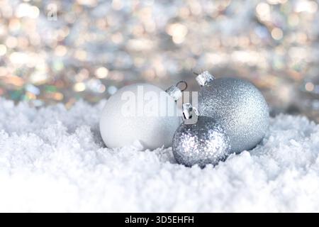 Silberne Weihnachtsschmuck auf Schnee mit Glitzer und sanfter Bokeh-Beleuchtung in einer festlichen Winterszene Stockfoto