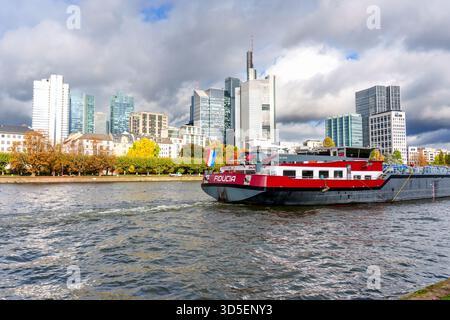 Frankfurt, Deutschland - 21. Oktober 2025: Die beeindruckende Skyline des Finanzviertels von Frankfurt, Deutschland, umrahmt den Main mit dem Fracht-Shi „Fiducia“ Stockfoto