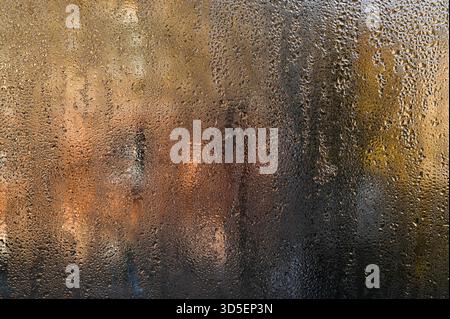 Nasses Glas. Winzige Feuchteperlen schmücken das beschlagene Fenster, den Hintergrund. Einige Tropfen rutschen langsam nach unten und hinterlassen flüchtige Spuren auf Glas. Abstrakte Ba Stockfoto