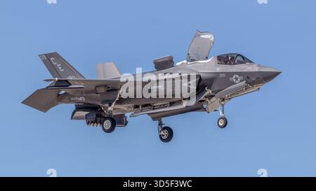 Ein US-Marine Corps F-35B Lightning II Tarnjäger schwingt im vertikalen Landemodus mit Fahrwerk gegen einen klaren blauen Himmel. Stockfoto