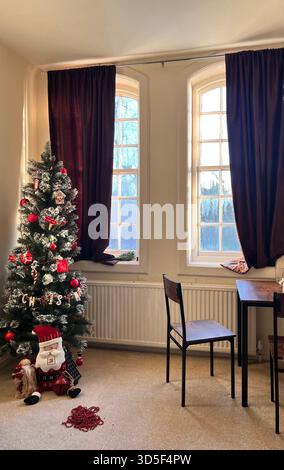 In einem gemütlichen Zimmer in Hull, England, befindet sich ein gemütlicher Innenbereich mit einem geschmückten Weihnachtsbaum in der Nähe eines Fensters. Stockfoto