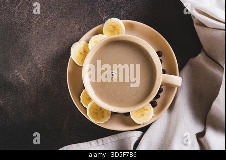 Nahaufnahme eines alternativen kalten Bananenkaffees in einer Tasse auf dem Tisch Stockfoto