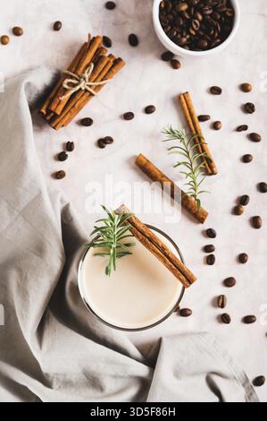 Tasse Eiskaffee mit Rosmarin und Zimt auf der Tischplatte und vertikaler Ansicht Stockfoto