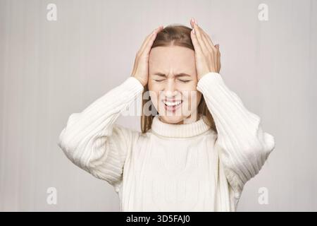 Junge Frau im Büro. Müde Augen. Weibliche Stress Lebensstil. Neue normale Ausbildung. Traurige Emotionen. Kopfschmerz-Konzept. Person mit hübschem Gesicht. Erschöpfter Arbeiter Stockfoto