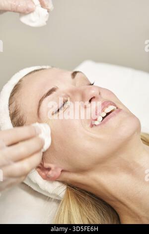 Im Spa-Salon wird eine Massage mit lächelndem Gesicht vorbereitet. Arzthände. Hübsche Patientin. Schönheitsbehandlung. Gesundheit Hautverfahren. Der Kopf der jungen Frau. Reinigung Re Stockfoto