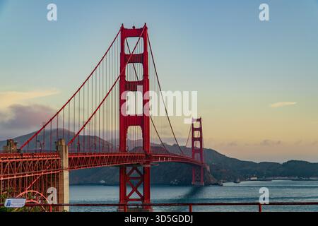 Die Golden Gate Bridge erhebt sich majestätisch in der Abenddämmerung und überspannt die San Francisco Bay mit atmosphärischen Wolken und weit entfernten Hügeln. Stockfoto