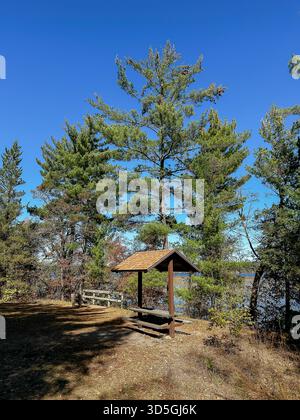 Eine Pause mit einem überdachten Picknicktisch und einer Bank entlang des Paul Bunyan Trail mit Blick auf den Lower Cullen Lake in Nisswa, Minnesota, in einem sonnigen Herbst Stockfoto