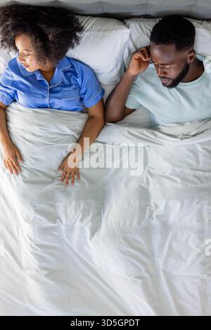 Ein Paar liegt im Bett, sieht nachdenklich aus und reflektiert ihren Tag Stockfoto