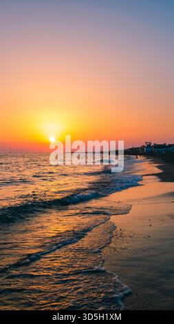 Sonnenuntergang am Mittelmeer. Natürliche Meereslandschaft mit ruhigen Wellen und heller niedriger Sonne. Seitlicher Blick auf das Wasser und den Strand. Das Konzept eines abendlichen Spaziergangs Stockfoto