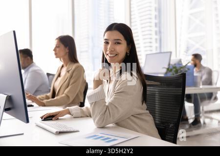 Glücklicher Analyst für asiatische Marketingagenturen, der bei Computer arbeitet Stockfoto