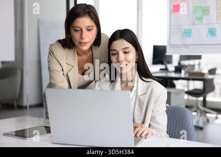 Junge Geschäftsleiterin hilft jungen Mitarbeitern bei Online-Projekten Stockfoto