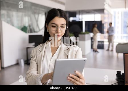 Geschäftliche Geschäftsfrau mit Brille, die auf einem Tablet-PC schreibt Stockfoto