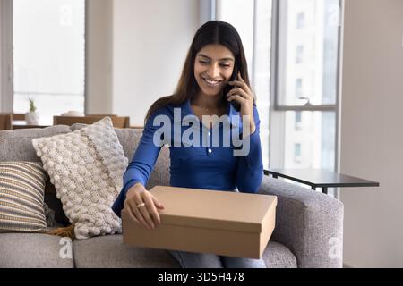 Positive junge Konsumentin mit Postkarton zu Hause Stockfoto