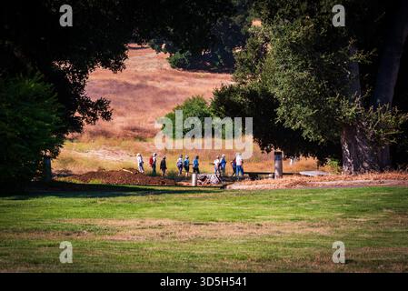 Eine Gruppe von Vogelbeobachtern spaziert an einem sonnigen Tag entlang eines grasbewachsenen Pfades unter großen Eichenbäumen auf der King Gillette Ranch, Kalifornien. Stockfoto