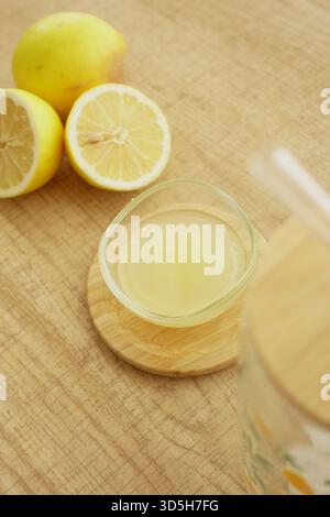 Erfrischender Zitronensaft und frische Zitronen auf einer Holzoberfläche Stockfoto