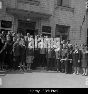 UdSSR, Ukrainische SSR, Slawjansk, 1975. Eine feierliche Versammlung von Kriegsveteranen, Beamten und Bürgern zum 30. Siegtag. Dieser Teil der stadtweiten Gedenkfeier findet im neuen Verwaltungsgebäude Raikom (Bezirkskomitee) in der Oktyabrskoy Revolyutsii Straße (heute Wassilevskaja Straße) statt. Die Archivfotos dokumentieren das Treffen von Ehrengästen und Anwohnern an diesem wichtigen Ort. Dieses Schwarzweiß-Foto zeigt einen großen sowjetischen Feiertag in den 1970er Jahren Stockfoto