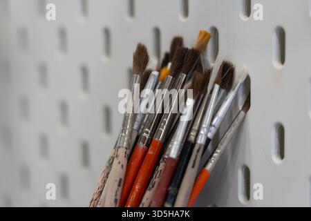 Pinsel mit braunen und weißen Borsten in einem Behälter gegen ein weißes Brett Stockfoto