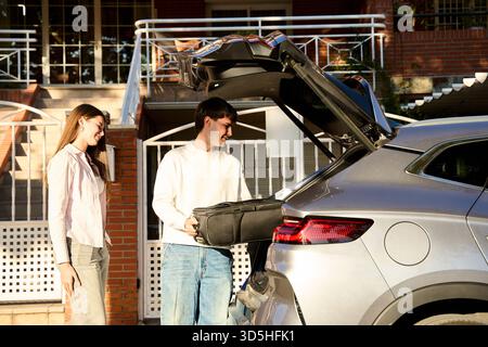 Ein junges Paar, das vor der Abreise Gepäck ins Auto lädt. Vorbereitung auf ein Reiseabenteuer und Sommerurlaub Stockfoto