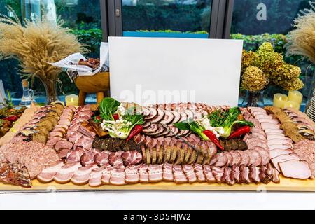 Große Wurstplatte mit verschiedenen Wurstwaren. Ein ausgeklügelter Wurstaufstrich mit einer großen Auswahl an aufgeschnittenem Fleisch, Würstchen, Kräutern und Stockfoto
