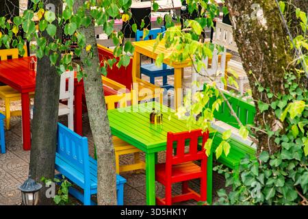 Lebhafte Holztische und -Stühle in einem Café im Freien schaffen eine lebhafte, einladende und charmante rustikale Atmosphäre Stockfoto
