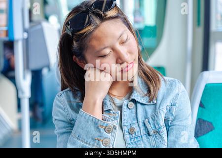 Chinesin schläft während der Fahrt mit öffentlichen Verkehrsmitteln tagsüber auf dem Zugsitz Stockfoto