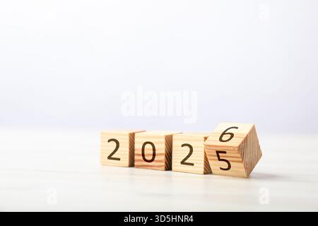 Neujahr. Kubus mit den Zahlen 5 und 6 wird umgedreht, um 2026 auf weißem Tisch vor hellem Hintergrund zu machen, Nahaufnahme Stockfoto