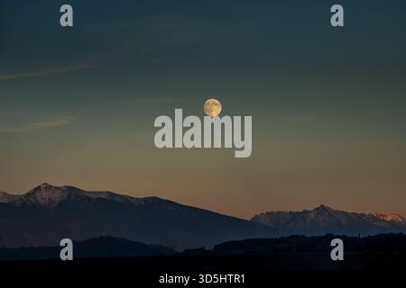 Großer Vollmond, der bei Sonnenuntergang über dem Gipfel Kriváň und der westlichen Tatra aufsteigt, Liptov, Slowakei. Stockfoto