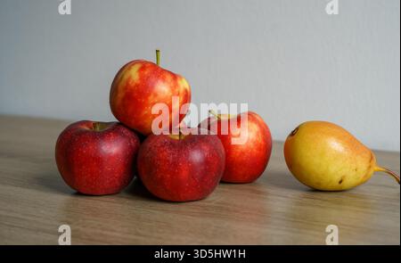 Stillleben im Herbst - frisch reife rote Äpfel und eine reife gelbe Birne auf einem Holztisch Stockfoto