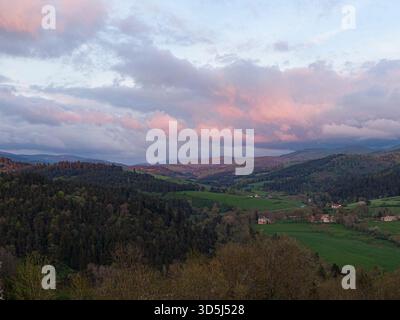 Der atemberaubende Sonnenuntergang überzieht den Himmel mit leuchtenden Farben über einem malerischen Tal und schafft eine ruhige und fesselnde Landschaft Stockfoto
